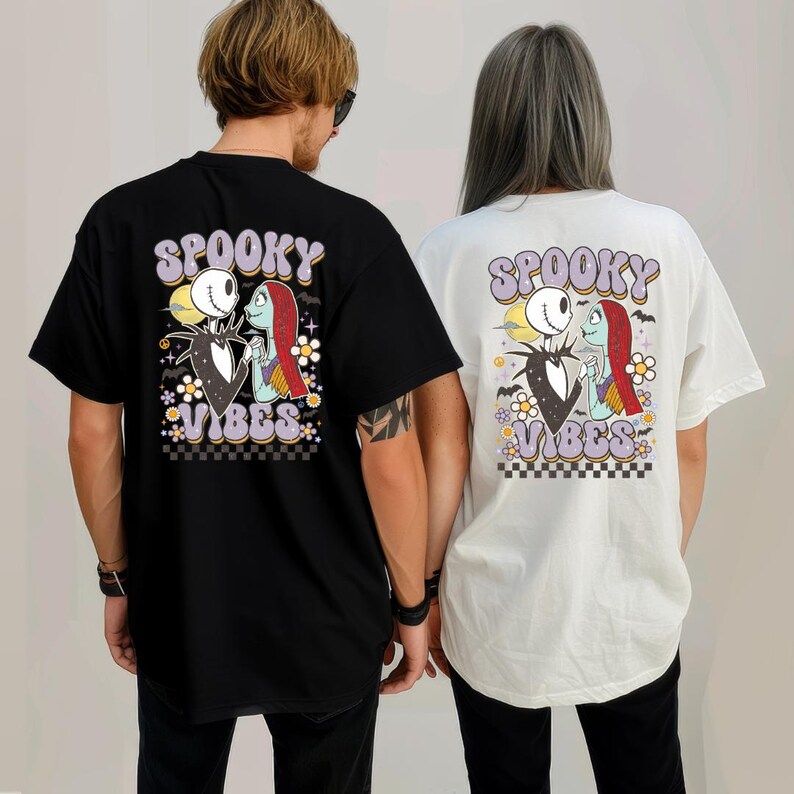 Puede incluir: Camisetas negras y blancas con un gr&aacute;fico de Jack Skellington y Sally de The Nightmare Before Christmas. Las camisetas tienen las palabras "Spooky Vibes" en una fuente retro, con detalles florales y de tablero de ajedrez.