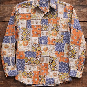 Peut inclure: Une chemise à manches longues avec un motif patchwork. La chemise présente des motifs floraux et géométriques dans des tons orange, bleu et crème. Elle a un col et une poche poitrine. Le tissu semble être du coton ou du lin léger.