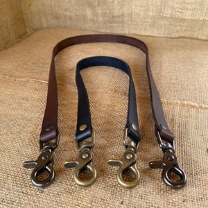 May include: Three leather straps with metal clasps. The straps are brown, black, and dark brown. The clasps are gold-toned.