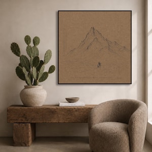 May include: A framed black and white mountain sketch on a brown background. The artwork is displayed above a rustic wooden bench with a cactus in a white pot. A beige, rounded armchair sits to the right.