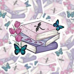 May include: A sticker depicting a stack of three books in shades of purple and pink, decorated with a black dragon silhouette, butterflies, and tulips. The top book is pink with a dragon illustration. The sticker has a white border.