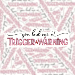 May include: A white sticker with pink and red text that reads "You had me at Trigger Warning". The text is outlined in black and has a flame symbol between the words "Trigger" and "Warning".