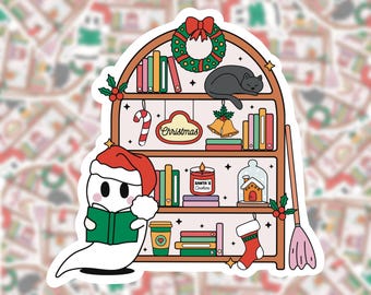May include: A white ghost wearing a Santa hat reads a book on a bookshelf decorated with Christmas ornaments, a cat, and a candy cane. The bookshelf has the word "Christmas" on a sign.