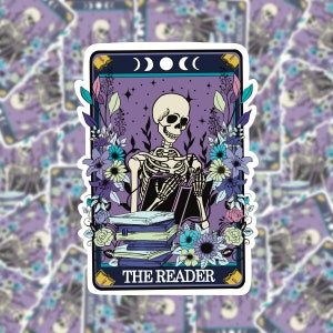 Peut inclure: Une illustration de carte de tarot représentant un squelette lisant un livre entouré de fleurs. La carte est violette avec une bordure bleu clair et le texte "THE READER" en bas.