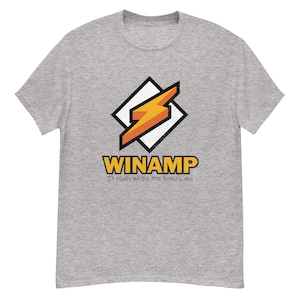 May include: A light gray t-shirt featuring the Winamp logo, a stylized orange lightning bolt within a white and black diamond shape. Below the logo, the word "WINAMP" is in yellow, with the phrase "It really whips the llama's ass" underneath.