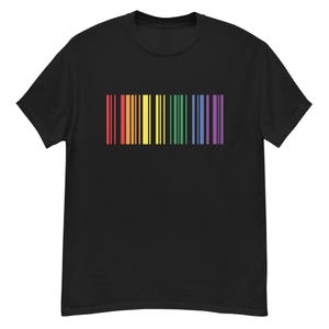 Puede incluir: Camiseta negra con un diseño de código de barras en los colores del arcoíris. El código de barras está compuesto por rayas verticales rojas, naranjas, amarillas, verdes, azules y moradas. La camiseta es de un material suave.