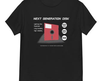 Op de afbeelding: Zwart T-shirt met een rode floppy disk-afbeelding en de tekst "NEXT GENERATION DISK". Het ontwerp bevat de woorden "Lightning fast", "Supersize", "Long durability" en "High reliability".