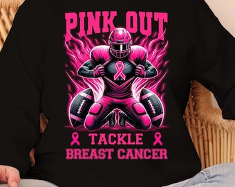 Puede incluir: Sudadera negra con un gráfico rosa de un jugador de fútbol americano con uniforme rosa, arrodillado con dos balones. El texto "PINK OUT" y "TACKLE BREAST CANCER" es rosa.