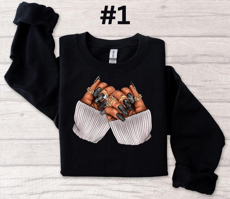 May include: Black sweatshirt with a graphic of two hands with long, black nails and gold rings. The hands are crossed over each other.