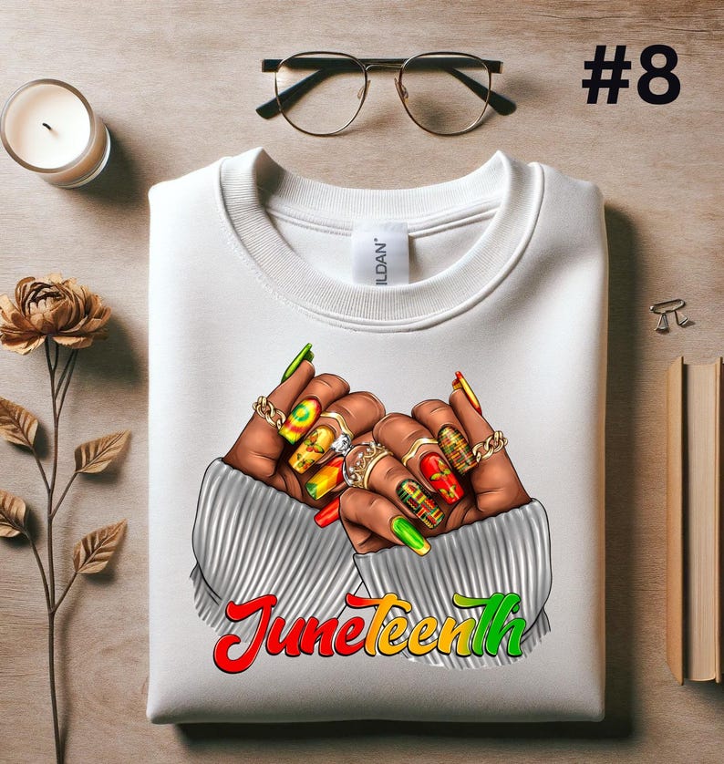 May include: White sweatshirt with a graphic of two hands with colorful nail polish and rings. The hands are clasped together and the text "Juneteenth" is printed below in red, yellow, and green.