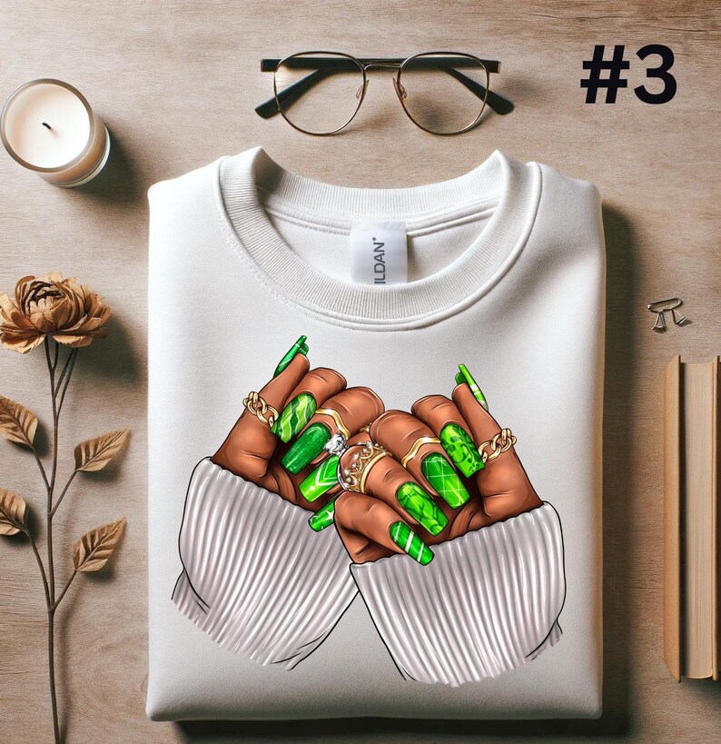 May include: White sweatshirt with a graphic of two hands with long green manicured nails and rings. The hands are in a heart shape.