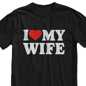 Puede incluir: Camiseta negra con texto blanco que dice "I love my wife" con un corazón rojo.