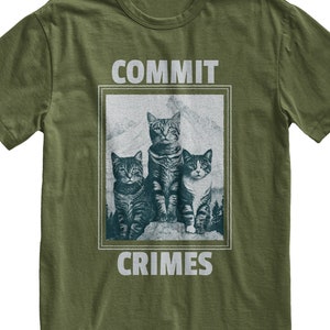 May include: Green t-shirt with a graphic of three cats in a mountain scene. The text "COMMIT CRIMES" is printed on the shirt.