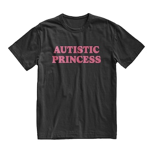 Puede incluir: Camiseta negra con el texto rosa "AUTISTIC PRINCESS" en el pecho. El texto est&aacute; en negrita, sin serifa. La camiseta tiene mangas cortas y cuello redondo.