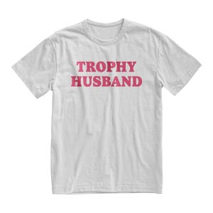 May include: White t-shirt with the text "TROPHY HUSBAND" printed in pink.