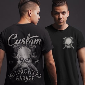 May include: Black t-shirt featuring a skull design with crossed wrenches and pistons. The shirt has the text "Custom Motorcycles Garage" and "Est. 1963" printed on it. The design is in shades of gray and white.