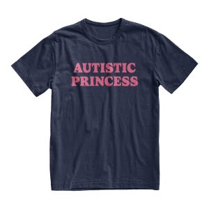 Puede incluir: Camiseta azul marino con el texto rosa "AUTISTIC PRINCESS" centrado en la parte delantera. La camiseta tiene mangas cortas y cuello redondo. La tela parece ser una suave mezcla de algod&oacute;n.