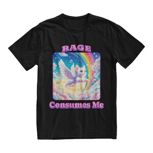 May include: Black t-shirt with a graphic of a white cat with wings flying through a rainbow in a cloud-filled sky. The text "RAGE CONSUMES ME" is printed below the graphic.