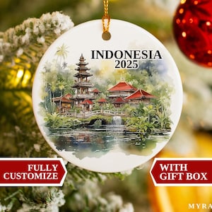 Könnte beinhalten: Runder, weißer Keramik-Weihnachtsschmuck mit einem Aquarellgemälde eines Tempels in Indonesien. Der Schmuck trägt den Text "INDONESIA 2025" und hängt an einem Weihnachtsbaum. Der Schmuck ist vollständig anpassbar und wird mit einer Geschenkbox geliefert.