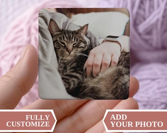 以下が含まれることがあります： 人のお膝の上で休んでいるトラ猫の写真が写った正方形の商品。「FULLY CUSTOMIZE」と「ADD YOUR PHOTO」の文字が入っています。Myra Grace Co.のロゴが下にあります。ソフトピンクと紫の背景。