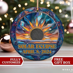 Peut inclure: Ornement rond avec un motif de vitrail représentant une éclipse solaire. L'ornement présente un soleil avec des rayons orange et jaunes, une lune gris foncé et le texte "SOLAR ECLIPSE APRIL 8, 2024". Il a une ficelle dorée pour l'accrocher.