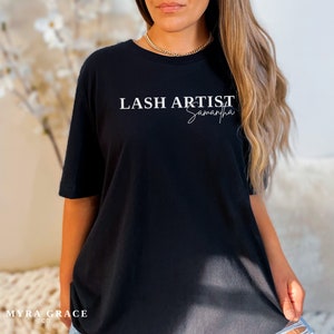 Pu&ograve; includere: T-shirt nero con la scritta bianca "LASH ARTIST Samantha". La maglietta ha maniche corte e girocollo. Il marchio "MYRA GRACE CO." &egrave; stampato in basso a sinistra.