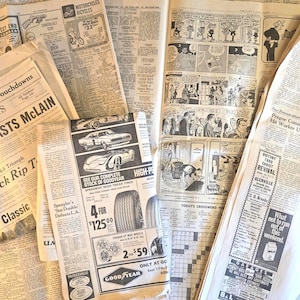 May include: A collection of vintage newspaper pages featuring black and white text, advertisements for Goodyear tires, motorcycles, and various local services. The pages include comic strips, a crossword puzzle, and headlines about events.