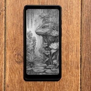 May include: A black smartphone displays a detailed grayscale illustration of a lizard-like creature emerging from lush aquatic plants and flowers. The artwork features lily pads, water, and hanging vines, creating a serene, natural scene.