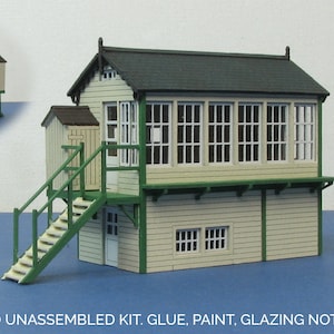 May include: Unpainted model kit of a two-story signal box with a green roof, green trim, and beige siding. The kit includes a small outbuilding with a green door.  UNPAINTED UNASSEMBLED KIT. GLUE, PAINT, GLAZING NOT INCLUDED.