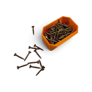 May include: A collection of metallic bronze-colored screws with sharp points and threaded shanks. Several screws are scattered outside, while a larger quantity is contained within a bright orange, rectangular, open-top plastic storage bin.