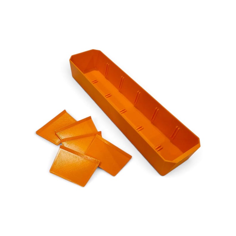 May include: A bright orange rectangular storage tray with internal vertical slots along the sides, accompanied by four separate orange rectangular dividers that can be inserted into the slots to create individual compartments within the tray.
