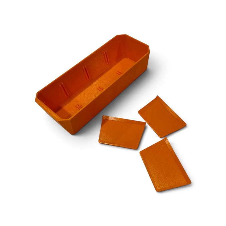 May include: A bright orange rectangular storage container with an open top and vertical interior slots for dividers. Three separate orange rectangular divider panels are positioned outside the container, ready to be inserted into the slots.