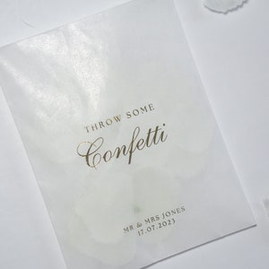 Pu&ograve; includere: Un sacchetto di carta bianco con la scritta dorata "Throw some confetti" e "Mr & Mrs Jones 17.07.2023".