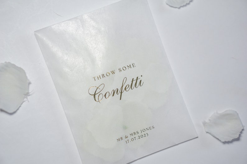 Pu&ograve; includere: Un sacchetto di carta bianco con la scritta dorata "Throw some confetti" e "Mr & Mrs Jones 17.07.2023".
