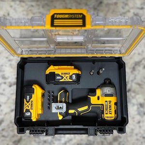 May include: A black and yellow DeWalt ToughSystem tool case with a clear lid. Inside are two 20V batteries, an impact driver, and various bits. The case is open, revealing the tools neatly arranged.