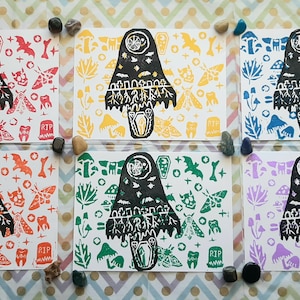 May include: Set of five prints featuring a black and white illustration of a mushroom with a face and a variety of other symbols. The prints are on white paper with a different colored background for each print: orange, yellow, green, blue, and purple.