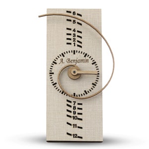 May include: A wooden clock with a spiral design and a wooden hand. The clock face has the text "A. Benjamin" and numbers 1 through 12. The clock is on a beige background.