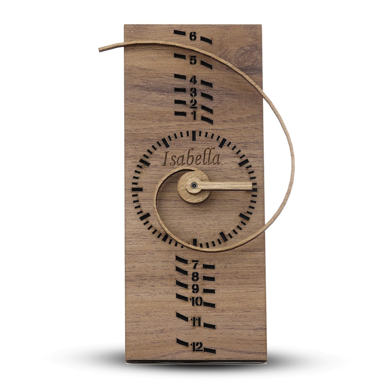 May include: A wooden clock with a spiral design and the name "Isabella" on the face. The clock has a wooden hand and a wooden frame.