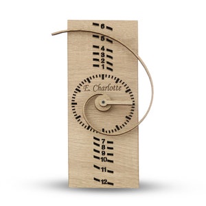 May include: Wooden clock with a spiral design and a personalized name, "E. Charlotte", on the face. The clock has numbers 1 through 12 on the outer edge and a small knob for setting the time.