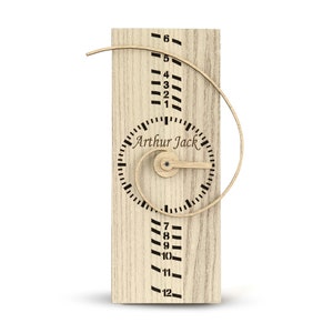 May include: A wooden growth chart with a spiral design and a clock face. The clock face has the text "Arthur Jack" and numbers 1 through 12. The growth chart has numbers 1 through 12 on the left side and numbers 1 through 6 on the right side.