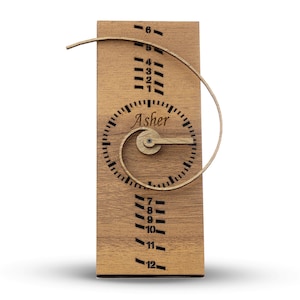 May include: Wooden growth chart with a spiral design and a clock face that says "Asher". The chart has numbers 1 through 12 on it.