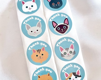 May include: Eight round blue stickers with white borders and the text "Thank you" in a retro font. Each sticker features a different cartoon cat with a variety of colors and patterns.