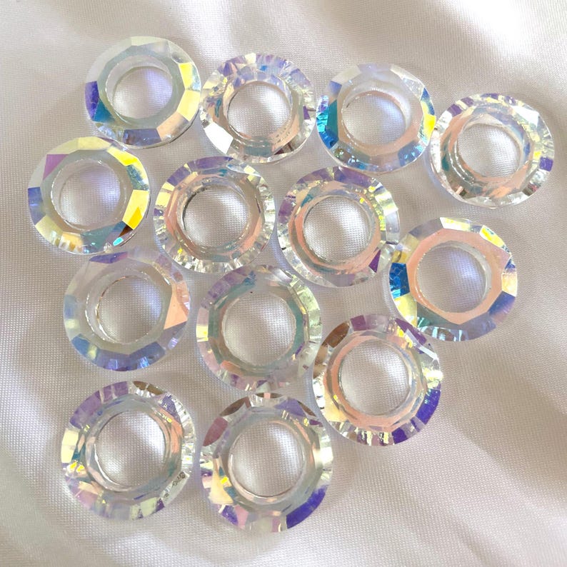 Pode incluir: Um grupo de 13 an&eacute;is de cristal de vidro transparente iridescente com um furo no centro. Os an&eacute;is s&atilde;o facetados e t&ecirc;m um efeito arco-&iacute;ris.