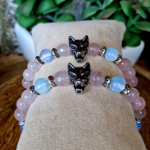 May include: Two bracelets with pink and blue beads and silver wolf head charms.