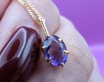 May include: A gold chain necklace with a purple oval gemstone pendant.