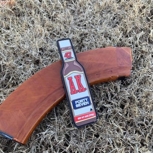 May include: A brown and black patch shaped like a bottle of hot sauce with the text "AK. FORTY SEVEN" and "NET WT 20OZ (591G)".