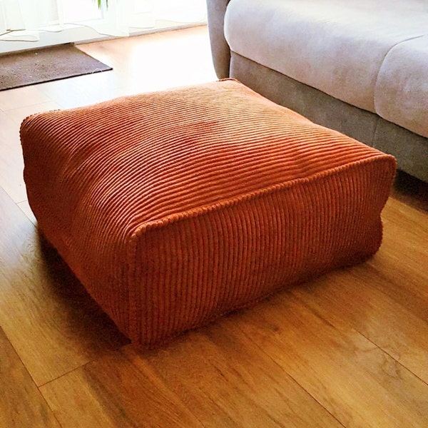 Corduroy stuffed sitting pouf, floor filled cushion seat, decorative pillow cover with insert, square ottoman in the corner in a bedroom