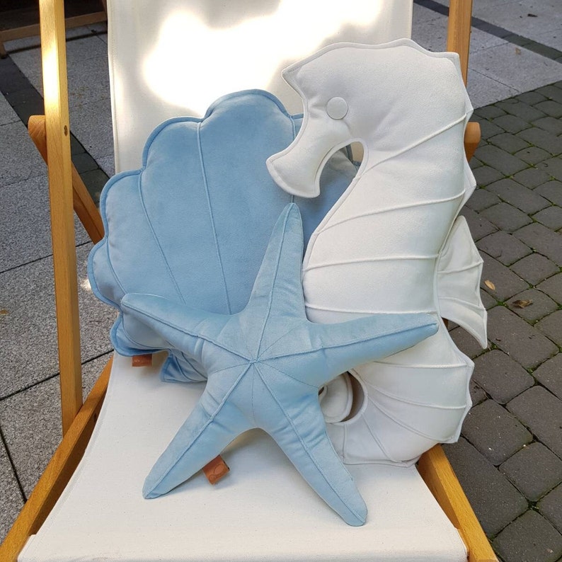 shell pillow with a starfish cushion as a nautical beach style decoration in the living room in the beachy themed room for baby boy and for a nursery bedroom