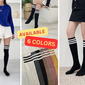 May include: Six pairs of knee-high socks in various colors, including white, gray, black, brown, pink, and yellow. Each sock has three white stripes at the top. The text "AVAILABLE 6 COLORS" is displayed on a yellow and red background.