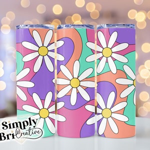 May include: Three stainless steel tumblers with a colorful abstract design featuring white daisies. The tumblers have a pink, purple, and green background with white daisies.
